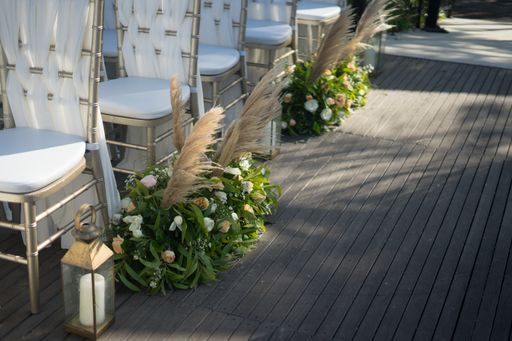 A high angle shot of beautiful white chairs decorated with flower compositions for a wedding ceremony