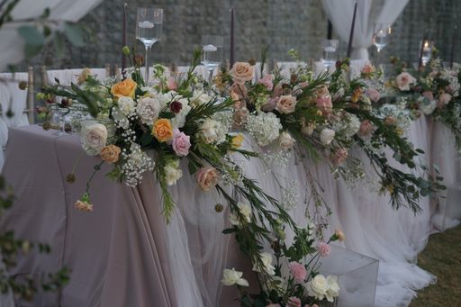 A closeup shot of a table with a white table clothing decorated with beautiful flowers for a wedding