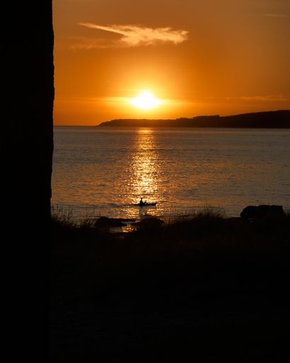 A vertical shot of a person on a canoe during sunset