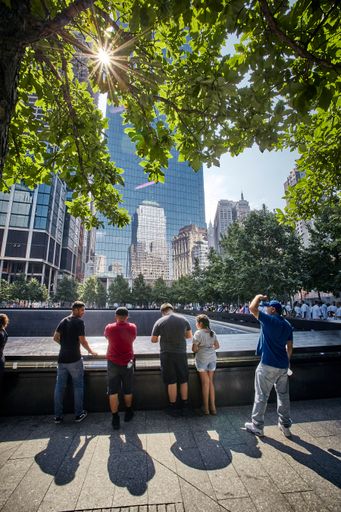 A vertical shot of people standing in front of New York buildings