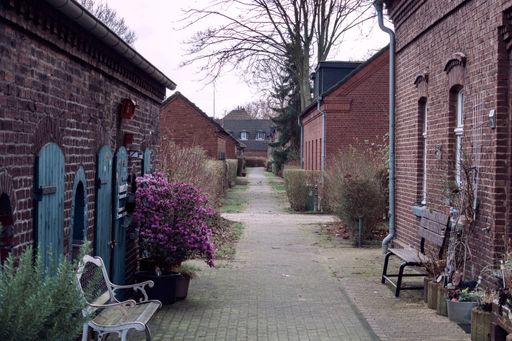 A perspective shot of a narrow walking path surrounded by brick houses.
