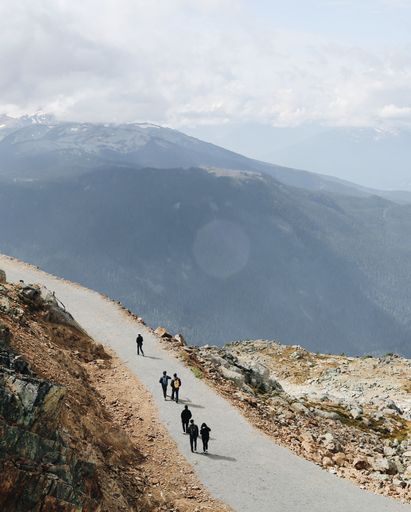 A vertical shot of a hiking path on a high mountain with people walking on it