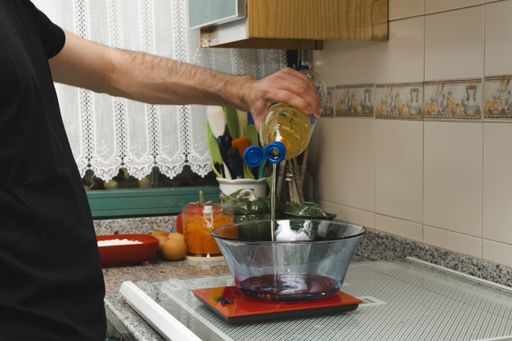 A man pouring the cooking oil into the bowl on a weighing  scale