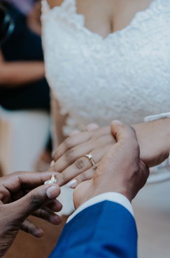 A closeup shot of a man putting a ring on his bride's finger