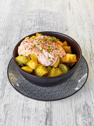 A closeup of a native Spanish dish called Patatas Bravas in a bowl