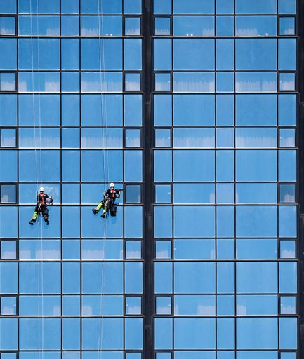 A low angle shot of two males cleaning a skyscraper facade