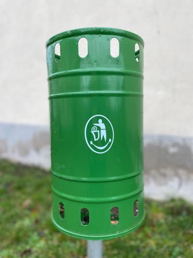 A green metal garbage bin outdoors
