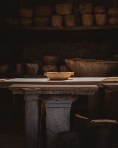 A vertical shot of a potter's workshop with earthenware on shelves and a plate on table in the middle