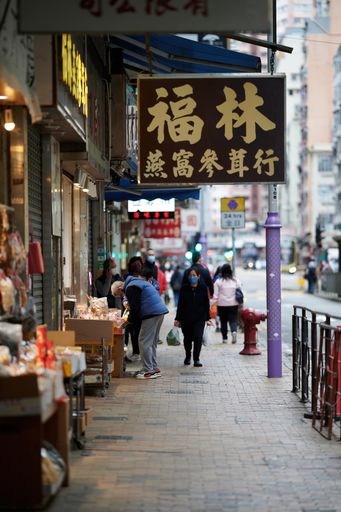 A vertical shot of a street with walking people and dried seafood shop in Sheung Wan, Hong Kong