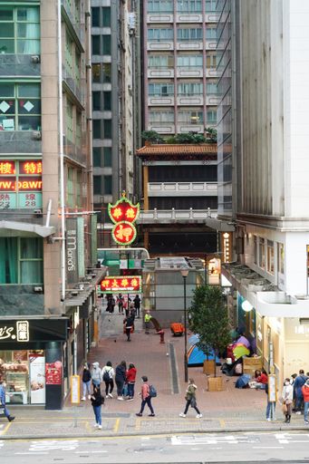 A vertical shot of a street full of people and tall buildings in Honk Kong