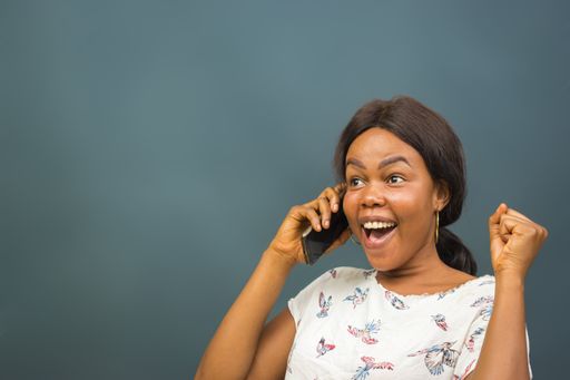 A young black businesswoman with strong expression of happiness celebrating success while talking on telephone