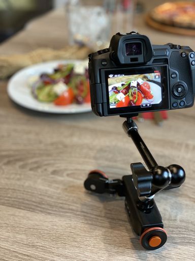 A selective focus shot of a camera with meal picture on the screen on the wooden table