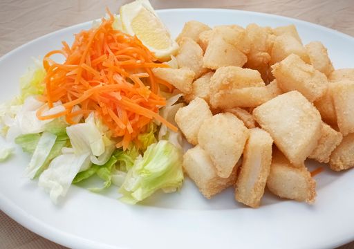 A closeup shot of friend chocos with salad garnish on a white plate