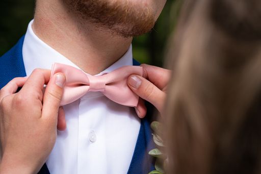 A closeup shot of a female holding the pink bow tie of the male