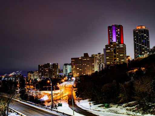 A beautiful scene of night streets, trees and urban colorful buildings against a gray night sky