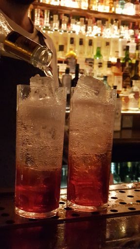 A vertical closeup shot of a bartender pouring beer into two glasses