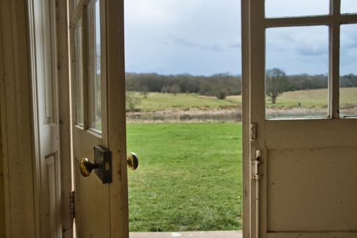 A shallow focus shot of an open door with a blurry view of a field at daytime