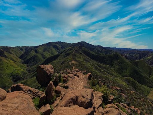 A view of a top of a mountain under a cloudy blue sky