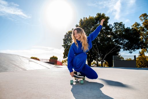 A Cheerful Caucasian woman with blonde hair skating in urban setting