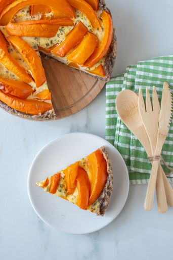 A vertical shot of a slice of pumpkin quiche Lorraine on a table