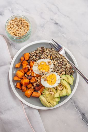 A vertical shot of a healthy bowl of quinoa, avocado, pumpkin pine nuts and eggs