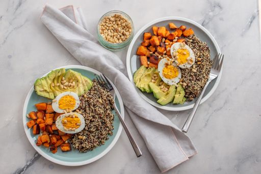 An overhead shot of healthy bowls of quinoa, avocado, pumpkin pine nuts and eggs