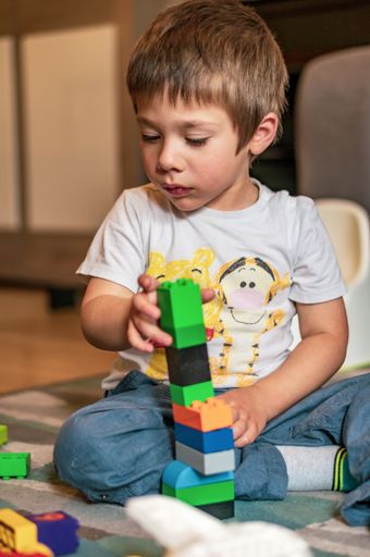 Small Polish Caucasian two years old boy sitting on a floor and playing with Lego Duplo.