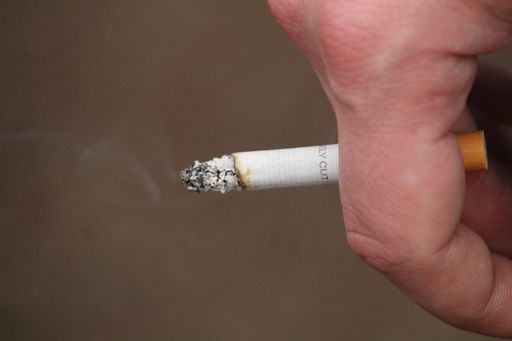 A closeup of a hand holding a lit cigarette