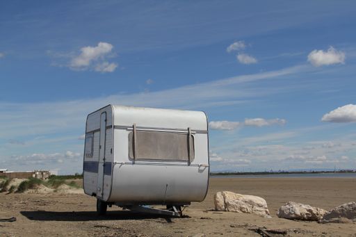 A shot of a white, old  travel trailer on the ground