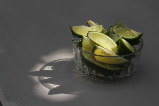 A closeup shot of the sliced fresh limes on the glass bowl under a sunlight