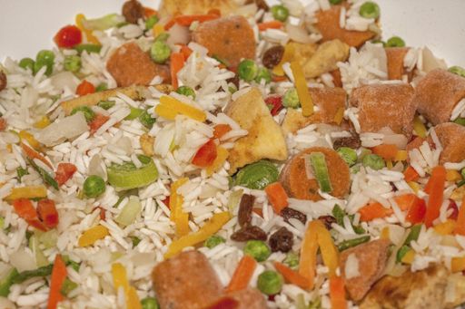 A closeup shot of freshly-made delicious fried rice with frozen vegetables in a pot