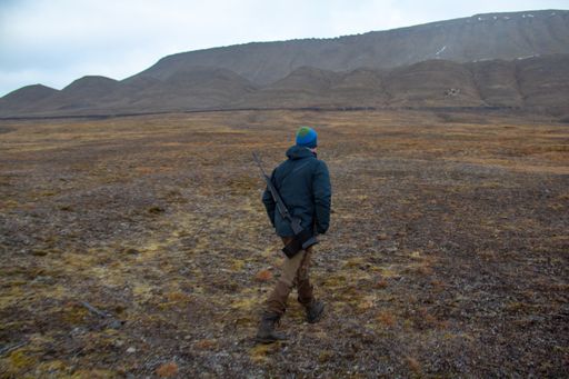 A hunter man with a sniper rifle going for hunting at winter