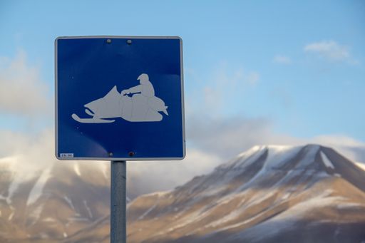 A snowmobile blue road sign in the mountains