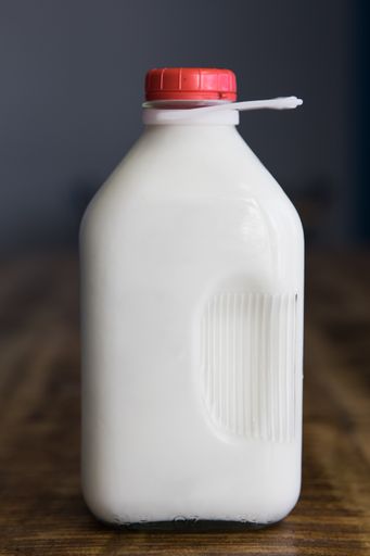 A vertical shot of an unlabeled glass jug of milk on the table