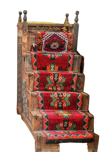 A vertical closeup shot of the wooden stairs covered with red patterned rug on the white background