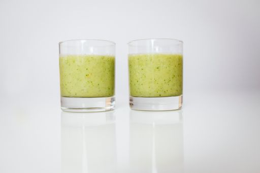 Two glasses of fresh green smoothie isolated on a white background