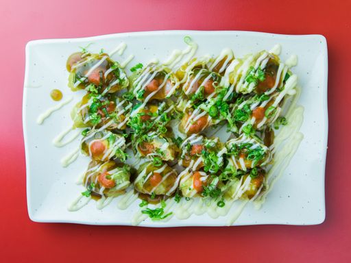 A top view of a plate of fried sushi dish served with mayo and sweet sauce