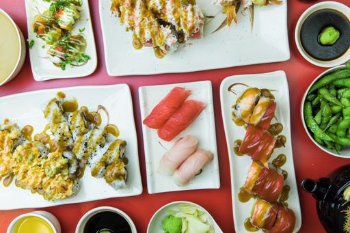 A closeup of sushi with various rolls, yellowtail nigiri, tuna nigiri, wasabi, edamame. Top view.