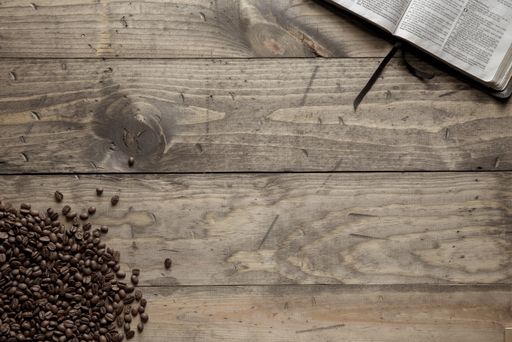 An overhead shot of coffee beans and an open book on a wooden table
