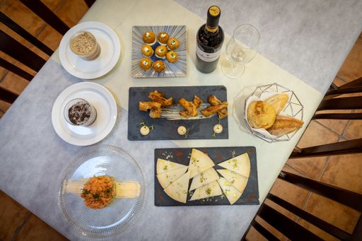 A top view of dinner with snacks and a wine bottle with a glass on a table