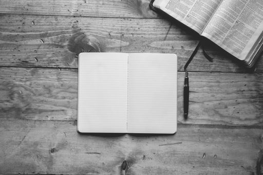 An overhead shot of a notebook near fountain pen in black and white