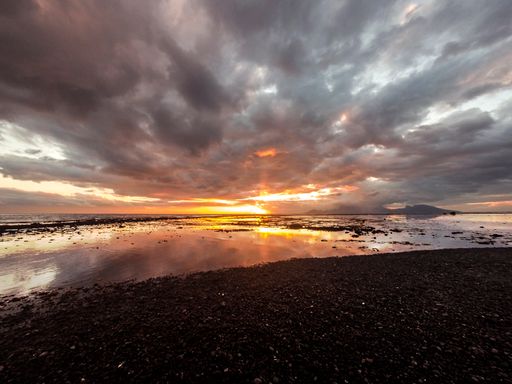 Tahitian Sunset with a mirror sea and a cloudy sky, Moorea island on the background