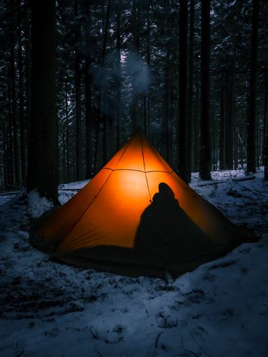 A beautiful shot of two people sitting inside the tent in a forest