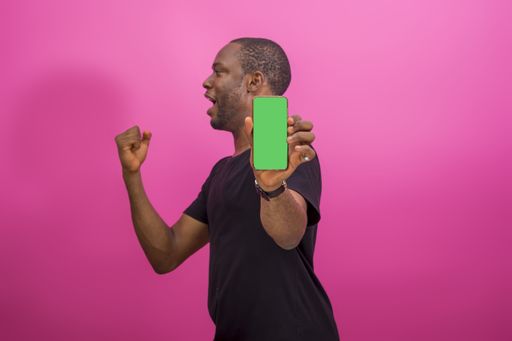 A young happy African american male using a smartphone isolated on a pink background