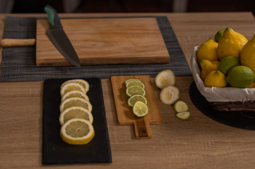 woman's hands cutting lemons and limes on a wooden board