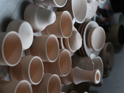 A vertical closeup shot of beautiful handmade clay pots and plates on a wooden table