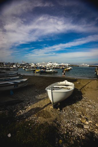 A vertical shot of a white boat moored on the shore. Capri island, Italy.