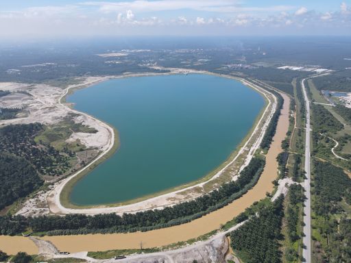 An aerial view of a lake surrounded with greenery under the blue cloudy sky