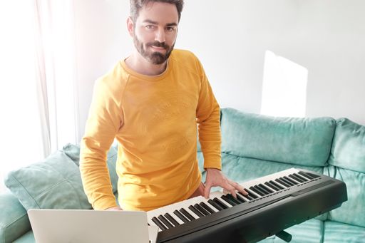 middle aged young man have fun playing and learning with digital piano at home