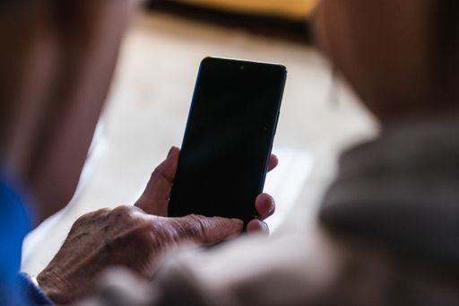A selective focus of a person holding and pointing on a smartphone with a blank black screen